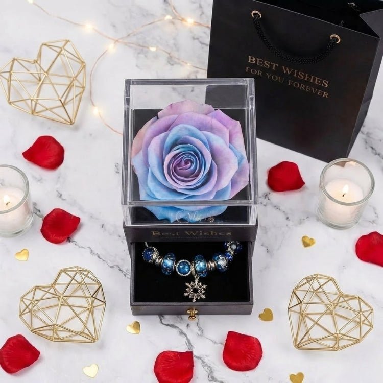 Flat lay photo of a blue and purple gradient preserved rose in a black gift box, surrounded by red petals and warm candlelight.