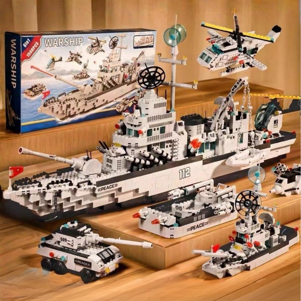 Full collection of the Kouvr 6-in-1 warship building block set displaying the main battleship, tank, helicopter, jet, and smaller boats on a wooden surface.