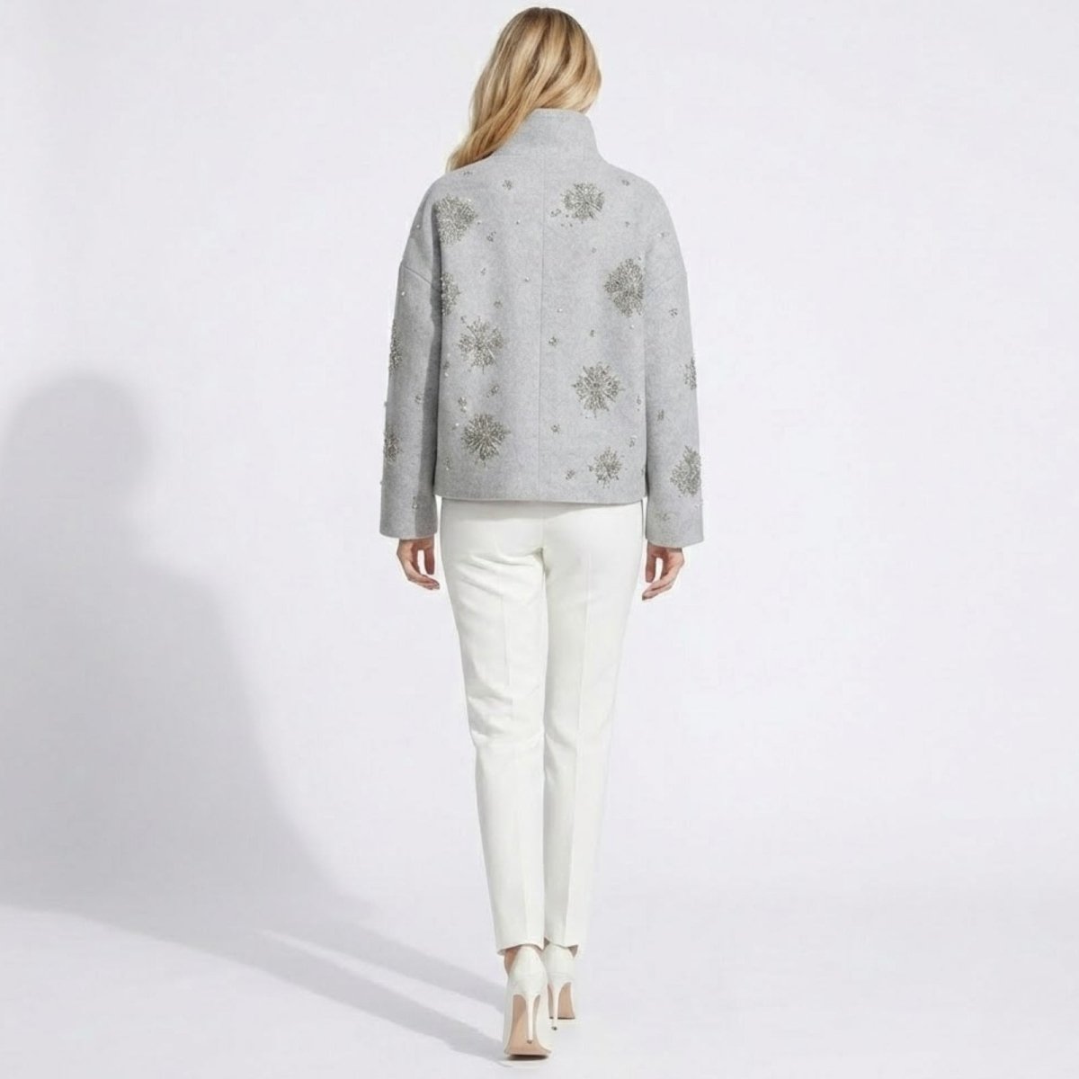 Back view of a model wearing the Kouvr Alisa light grey wool jacket, showcasing the intricate crystal snowflake beading across the back and sleeves.