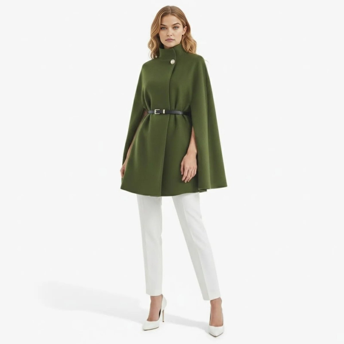 Model wearing the Kouvr olive green belted funnel neck cape coat with white trousers, shown from the front against a white background.