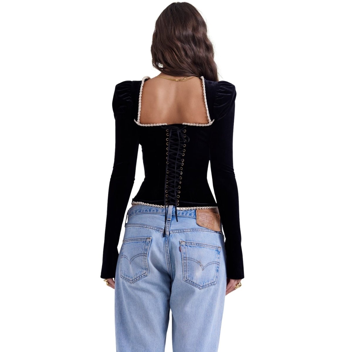 Person wearing a black kouvr long-sleeve top with cut-out design and light blue jeans on a white background