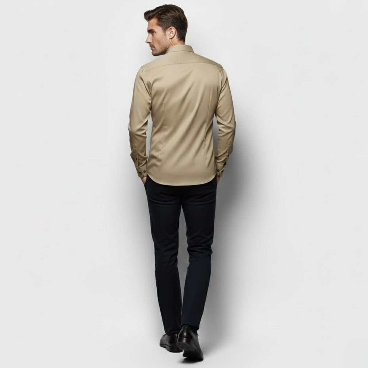 Back view of a male model wearing the Kouvr Briar khaki performance dress shirt, showing the back darts and slim silhouette.
