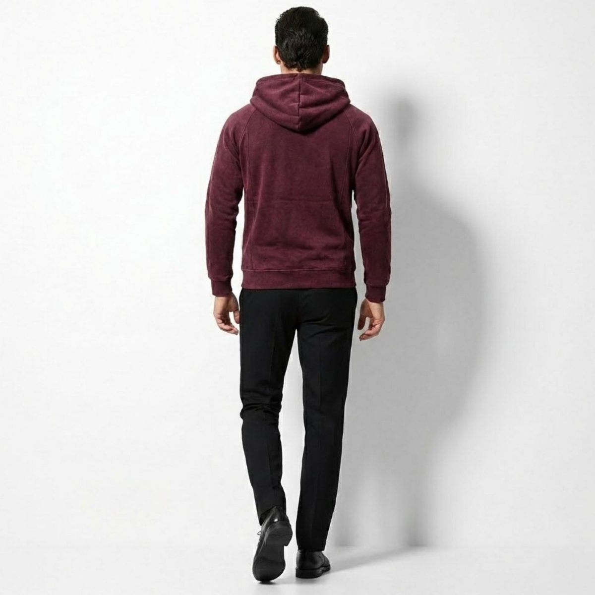 Back view of a male model wearing the Kouvr burgundy hoodie, displaying the structure of the hood and the slim fit.