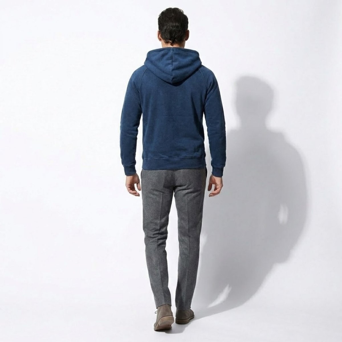 Back view of a male model wearing the Kouvr blue hoodie, showing the structure of the hood and shoulders.