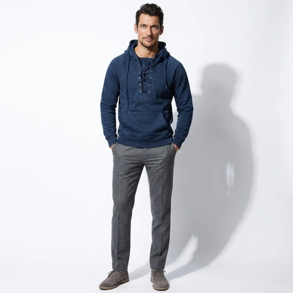 Male model wearing the Kouvr blue lace-up henley hoodie, standing forward with hands in pockets of grey trousers.