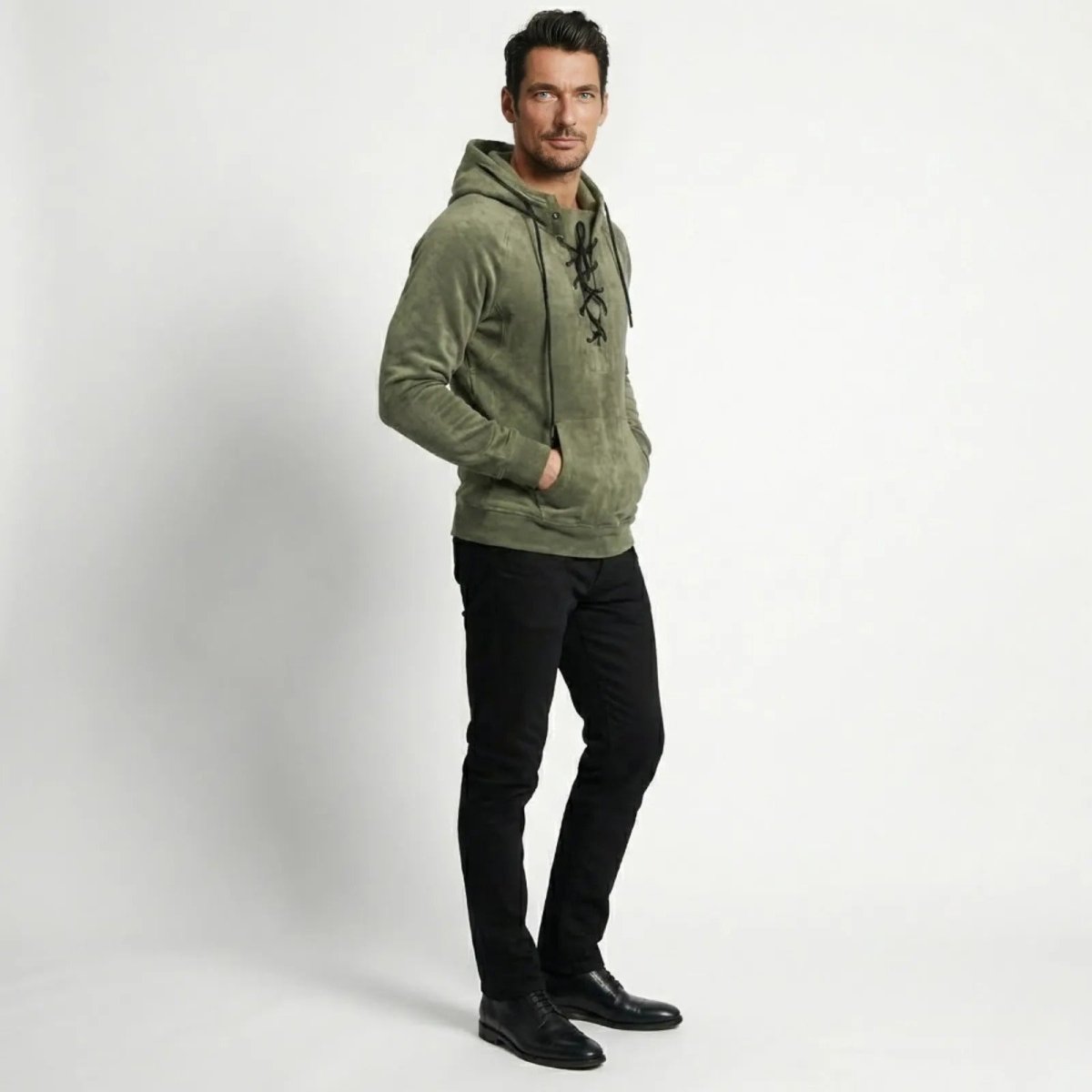 Side profile of a male model in the olive green Kouvr Cannon lace-up hoodie showing its modern fit and sleeve detail.