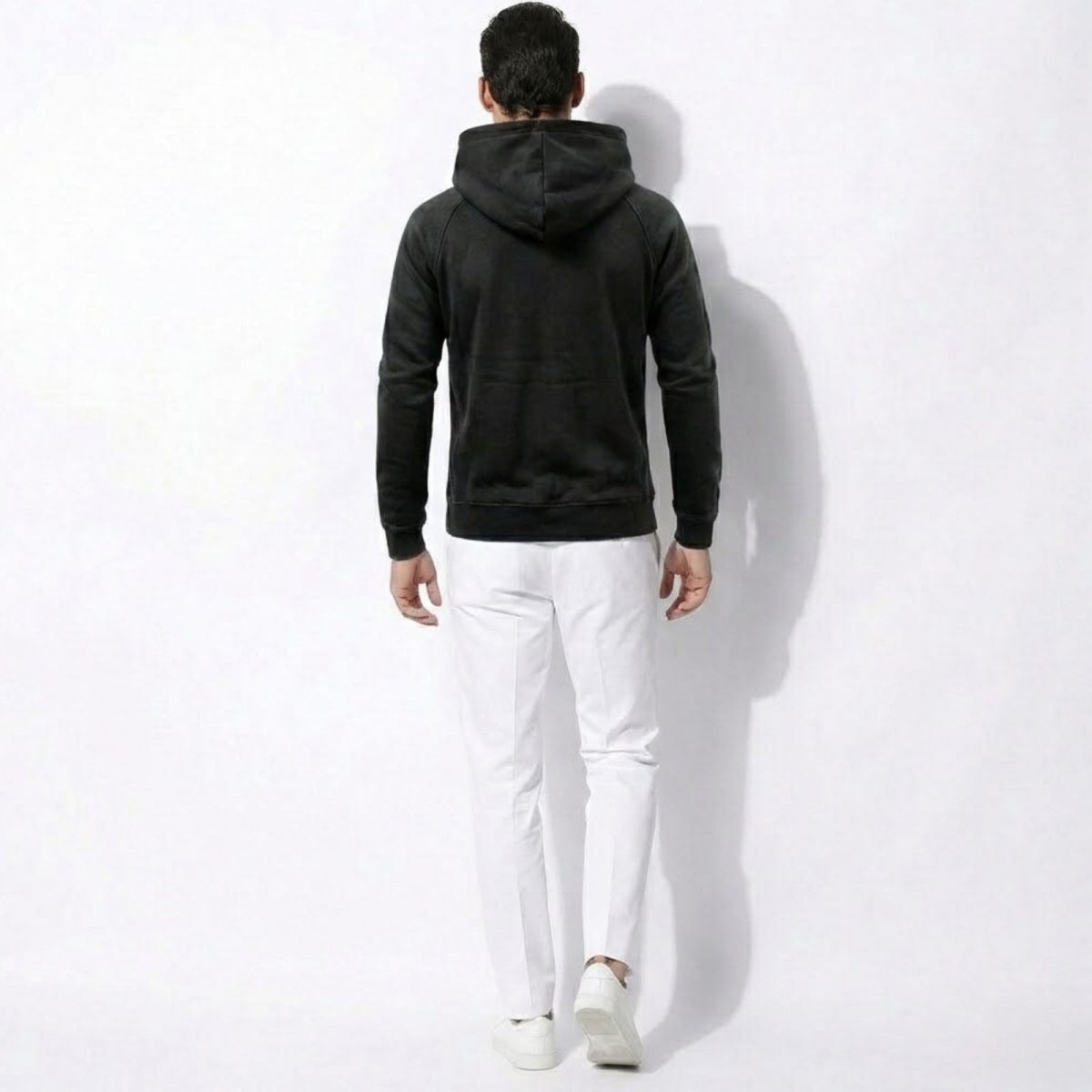 Back view of a male model wearing the Kouvr Cannon washed black hoodie, showcasing the hood and fit across the shoulders.