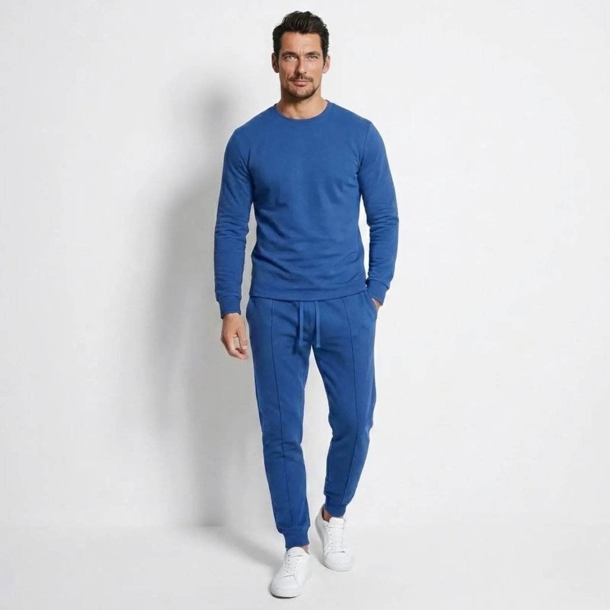 Model wearing the blue Crue men's lounge set by Kouvr, featuring a slim fit crewneck sweatshirt and tapered joggers.