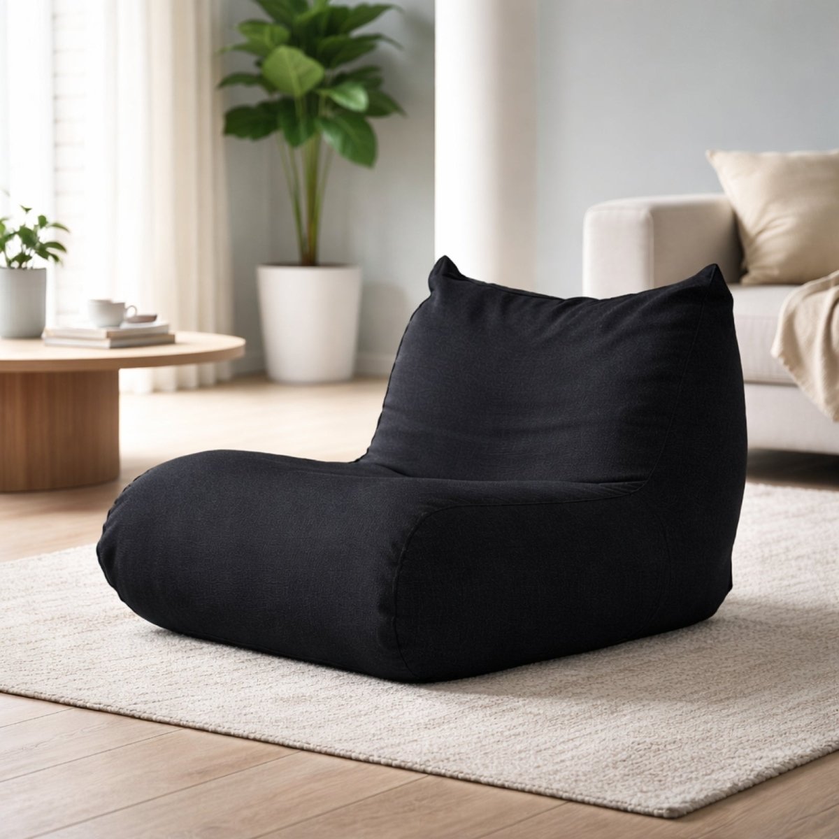 Matte black single seater floor sofa with high density foam structure placed next to indoor plants.