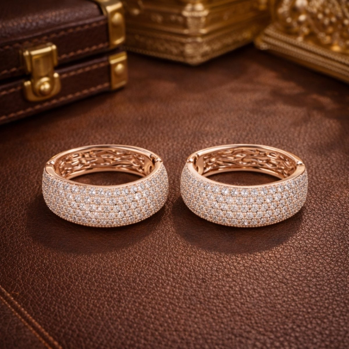 A close-up view of the Kouvr Emmiline diamond hoop earrings resting on a rich brown textured leather surface, highlighting their brilliant sparkle.