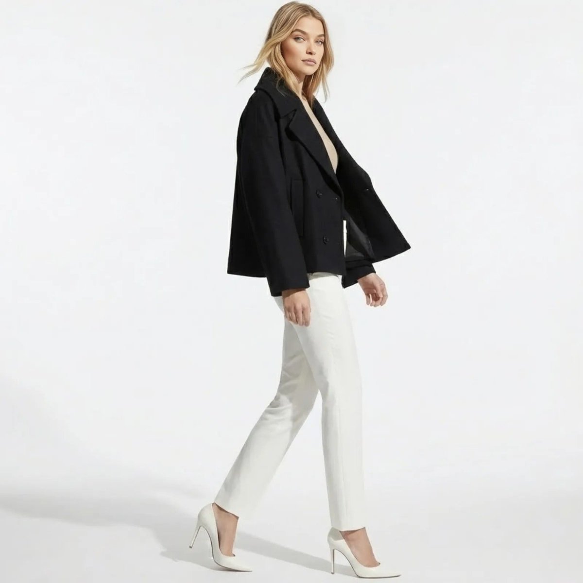 Side view of a model walking in the black cropped wool peacoat, showcasing its A-line silhouette and sleeve length.
