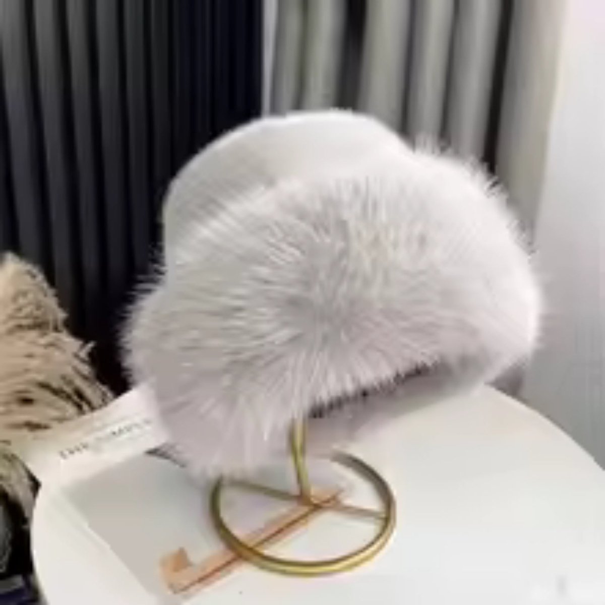 grey fluffy hat on a stand with a blurred background