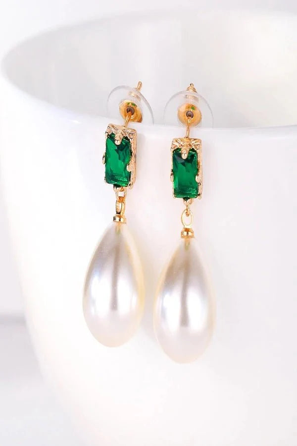 Gold Kouvr earrings with green gemstones on a white background