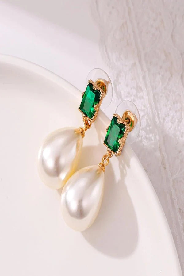 Earrings Kouvr with green gemstones and pearl-like droplets on a white surface