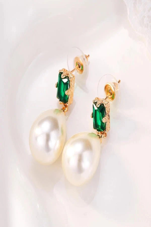 Pearl Kouvr earrings with green gemstones on a white background