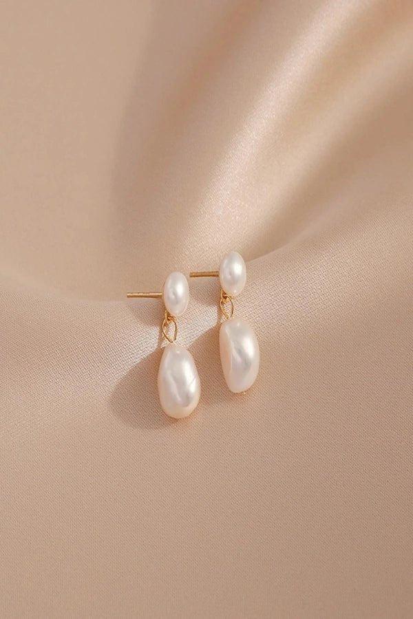 Pearl Kouvr earrings on a beige fabric background