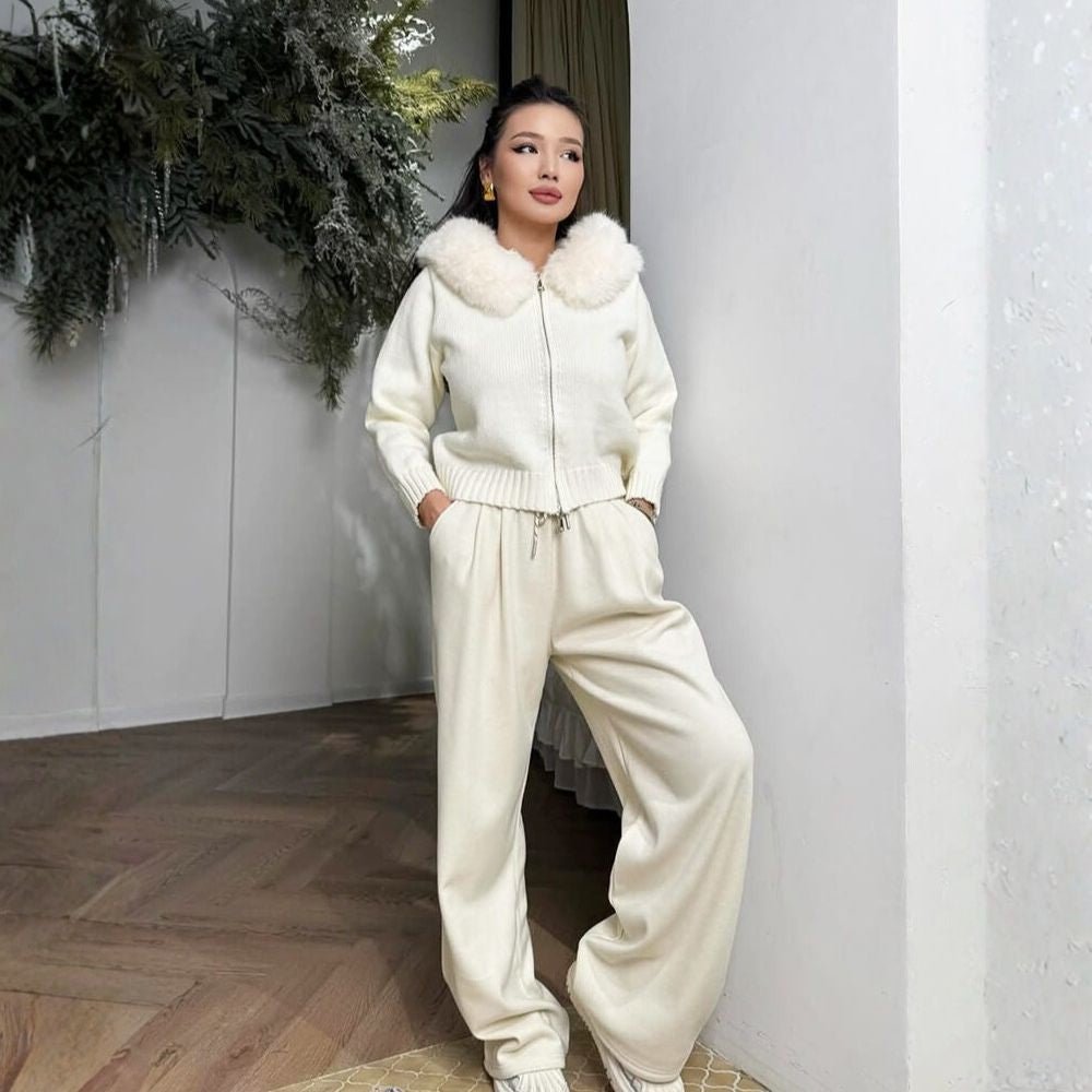 Woman wearing a ivory kouvr outfit with fur trim in a room with decorative plants.