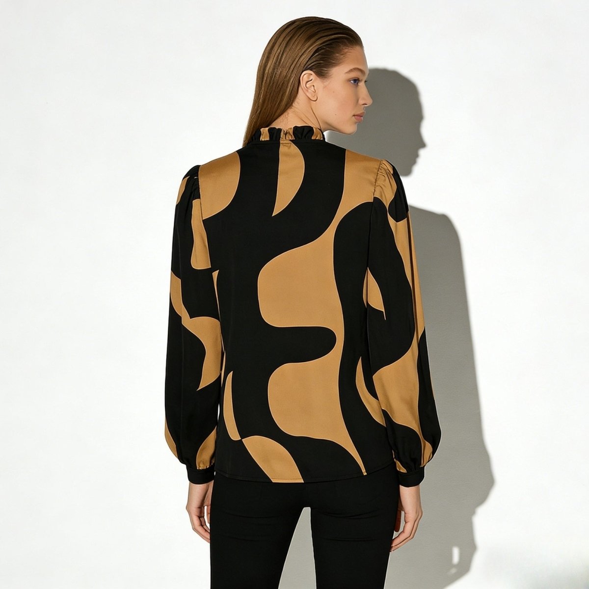Back view of the Judith blouse showing the high ruffled mock neck and the continuation of the bold black and tan pattern.