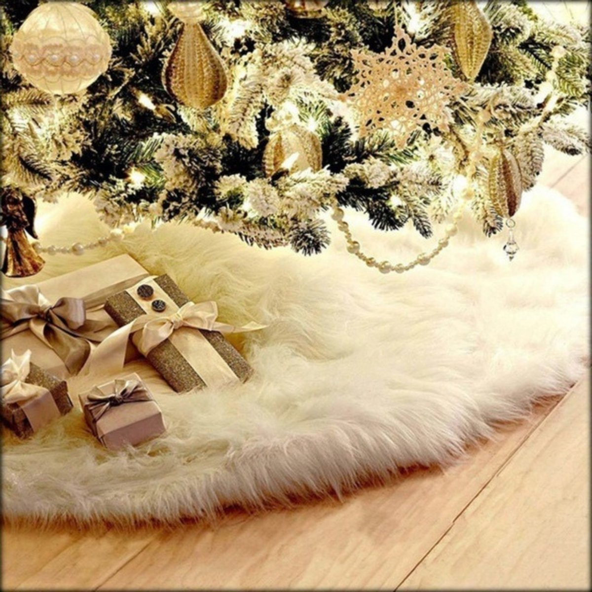 A luxurious white faux fur Christmas tree skirt from Kouvr Fashion at the base of a beautifully decorated tree with elegant gold and silver presents.