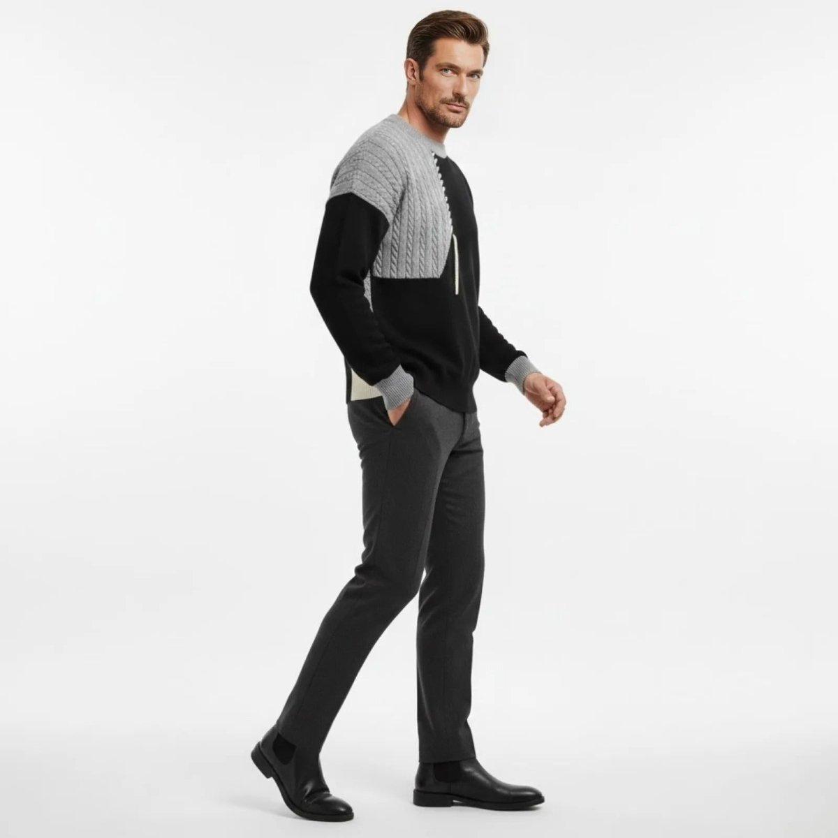 Male model in a walking side profile pose showing the texture and fit of the Kouvr Fashion color block patchwork sweater.