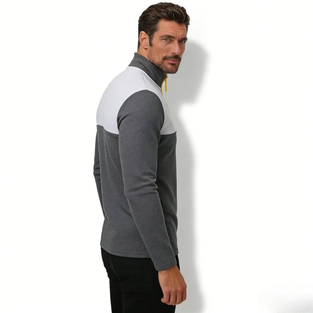 Side profile of a man in the Kouvr Fashion charcoal grey and white colorblock performance quarter-zip sweater.