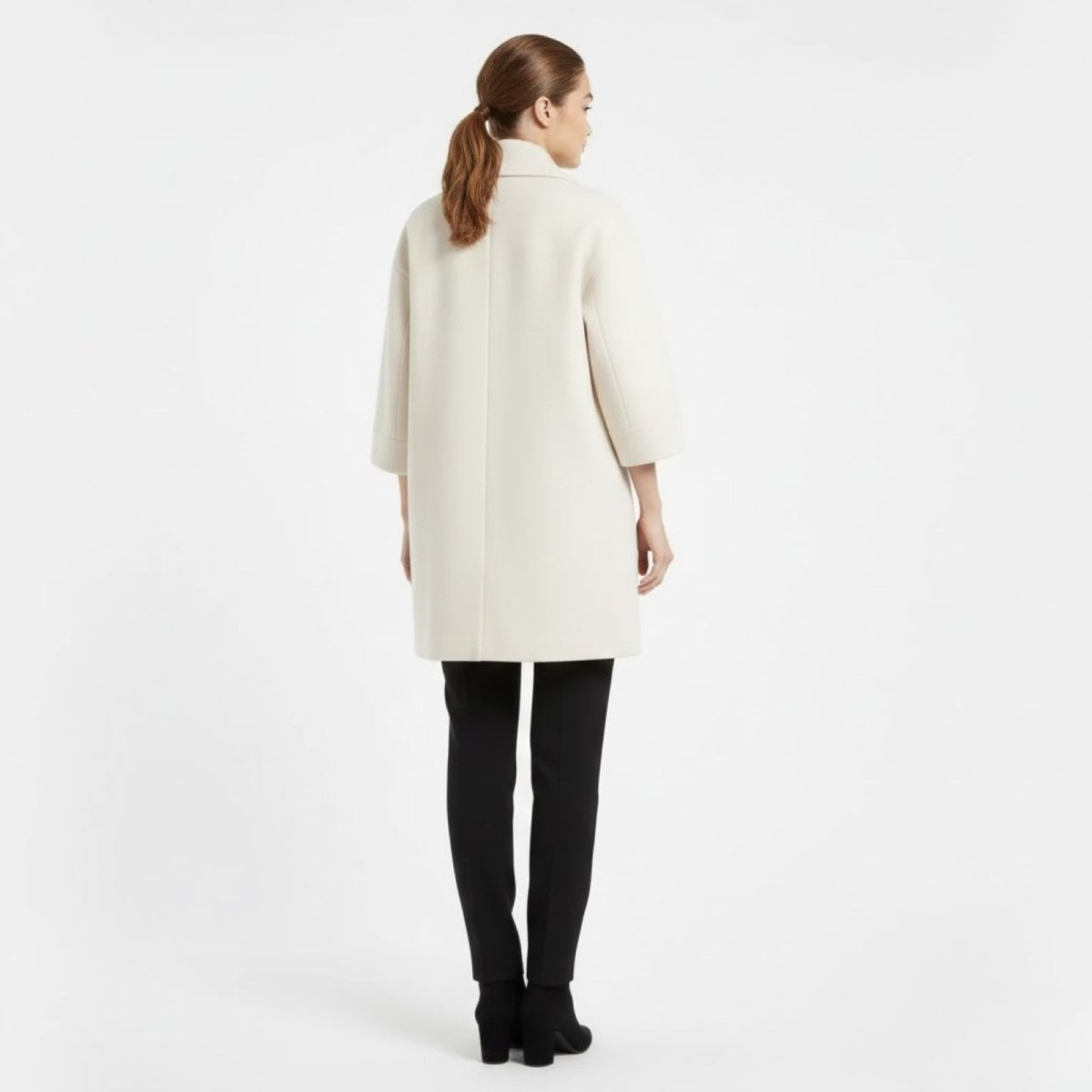 Back view of a model in the Kouvr Fashion white minimalist car coat.