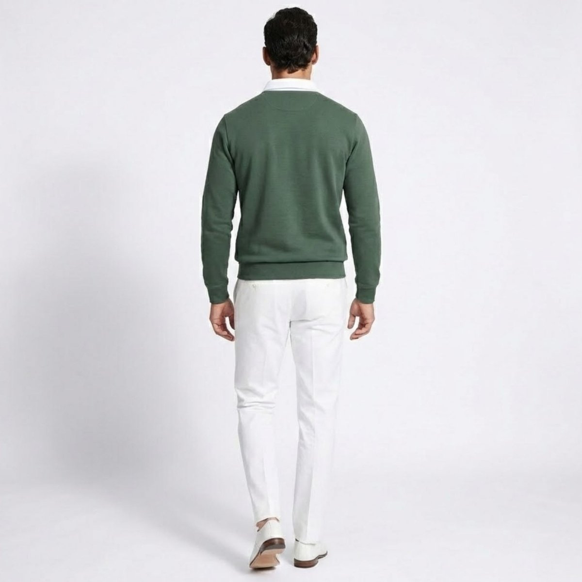 Back view of a man wearing the Kouvr green knit polo sweater with white trousers.