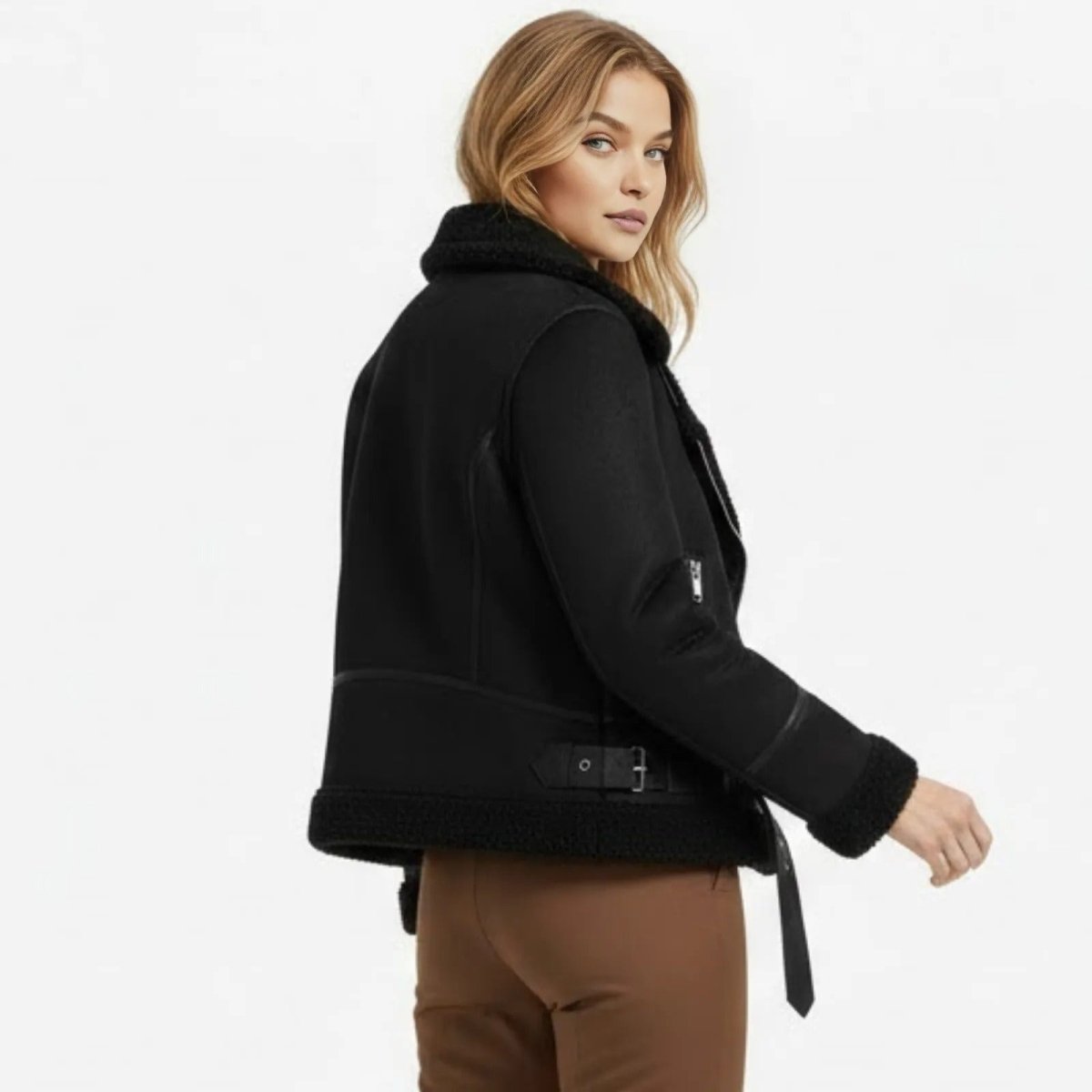 Back view of a woman looking over her shoulder in the Kouvr Katelynn black shearling biker jacket, highlighting the seaming and hem belt detail.