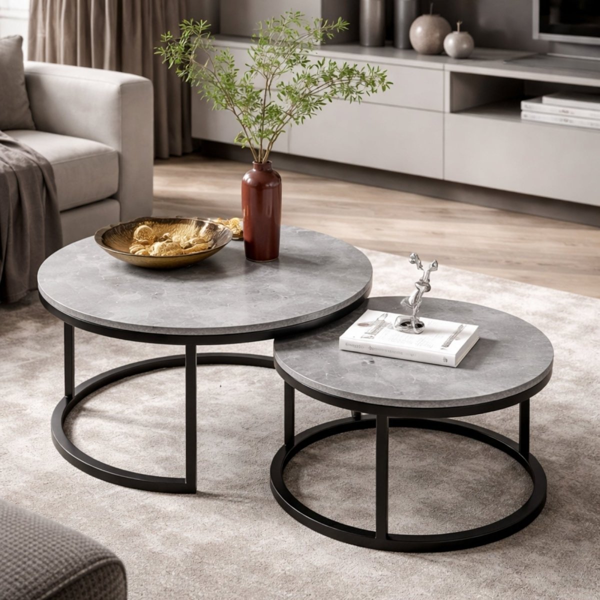 Modern round nesting coffee table set with grey concrete-look sintered stone top and black metal frame in a luxury living room.
