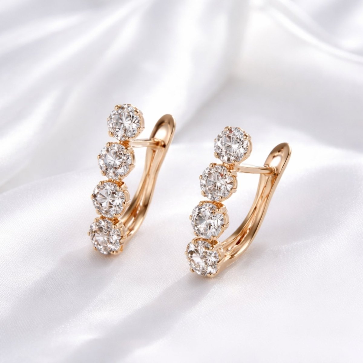 Elegant Kouvr four-stone earrings in 585 rose gold with brilliant zircons resting on a luxurious white silk background.
