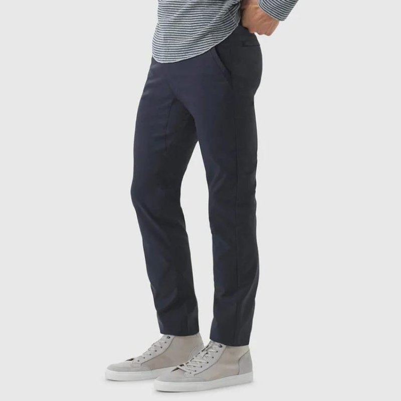 Close-up detail shot of the Kouvr All-Day Commuter Pant in navy, showing the technical fabric, front slash pocket, and button closure.