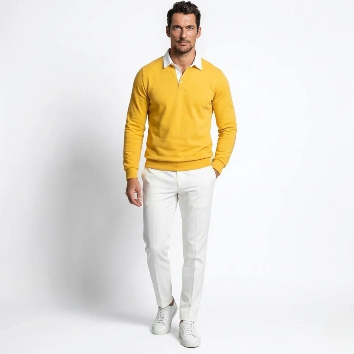 Male model wearing the Kouvr yellow long sleeve knit polo sweater with a white collar, paired with white trousers.