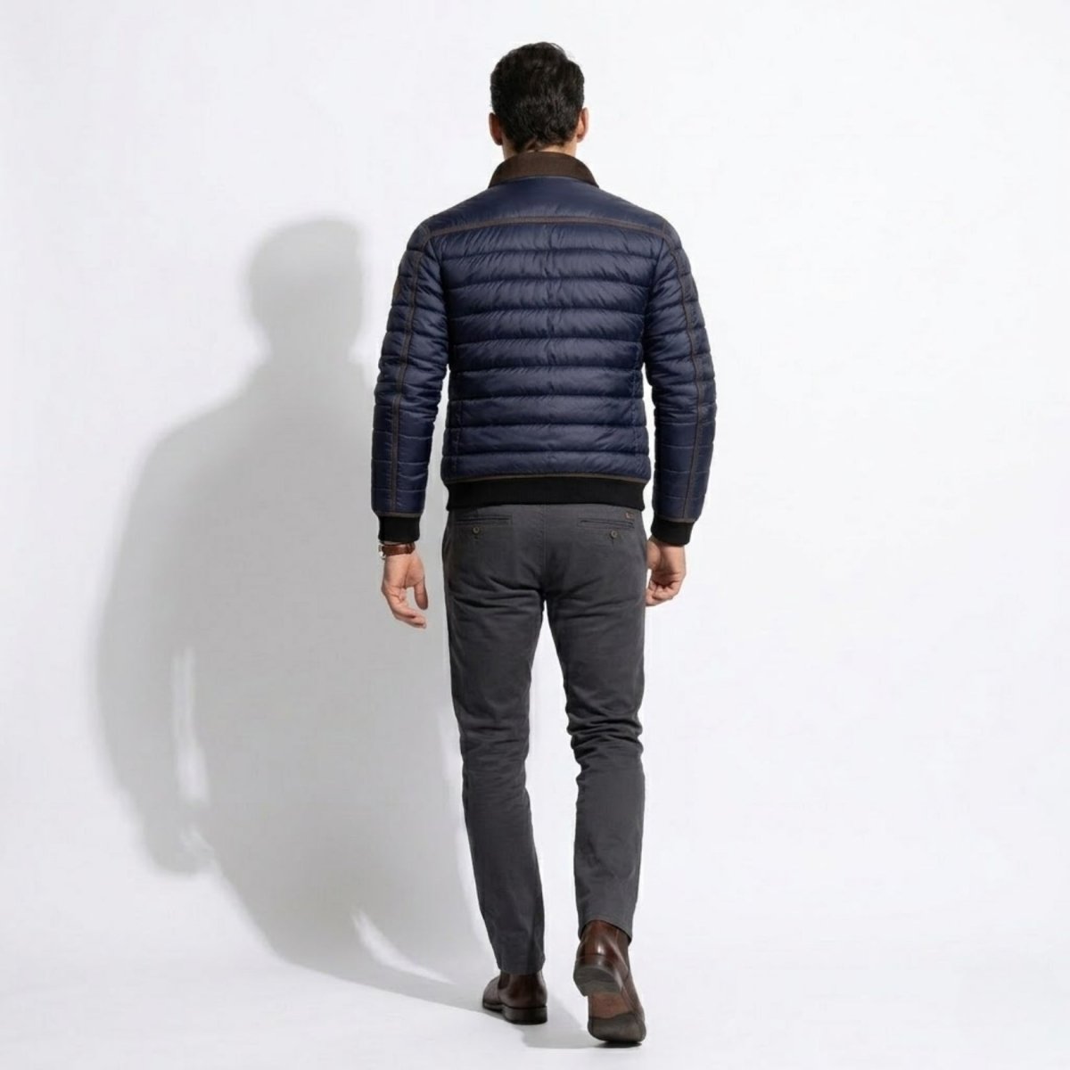 Back view of male model demonstrating the tailored fit and black ribbed hem of the Kouvr winter outerwear jacket.