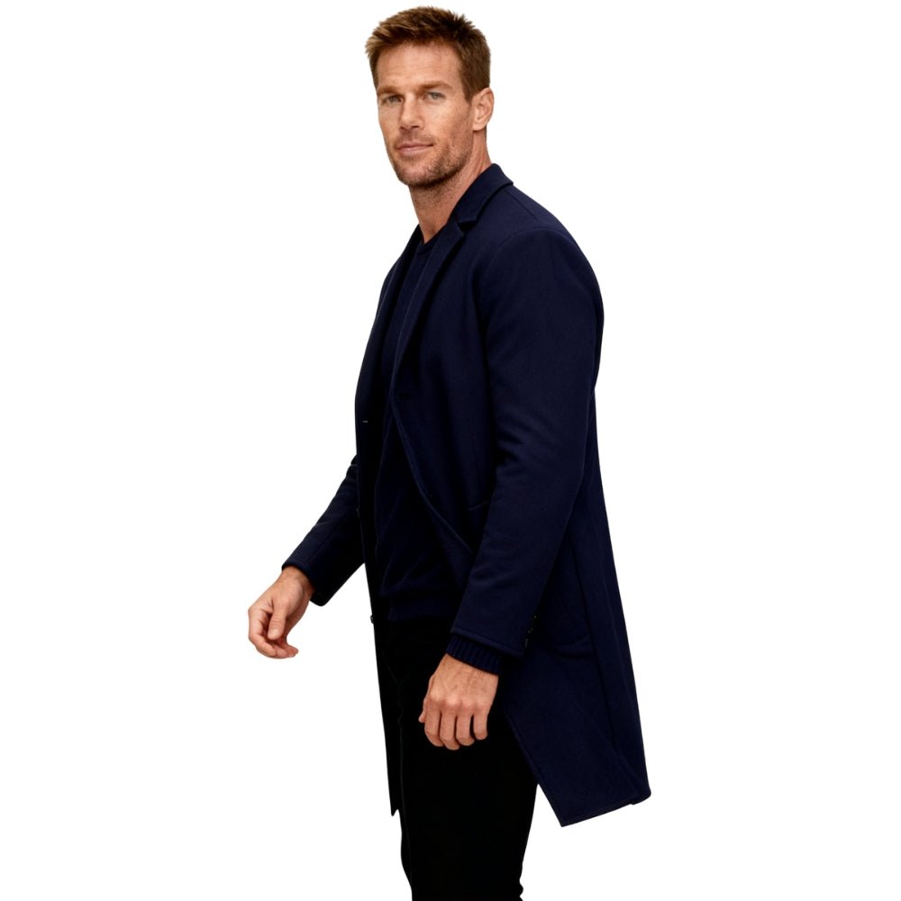 Man wearing a navy blue Kouvr overcoat on a white background