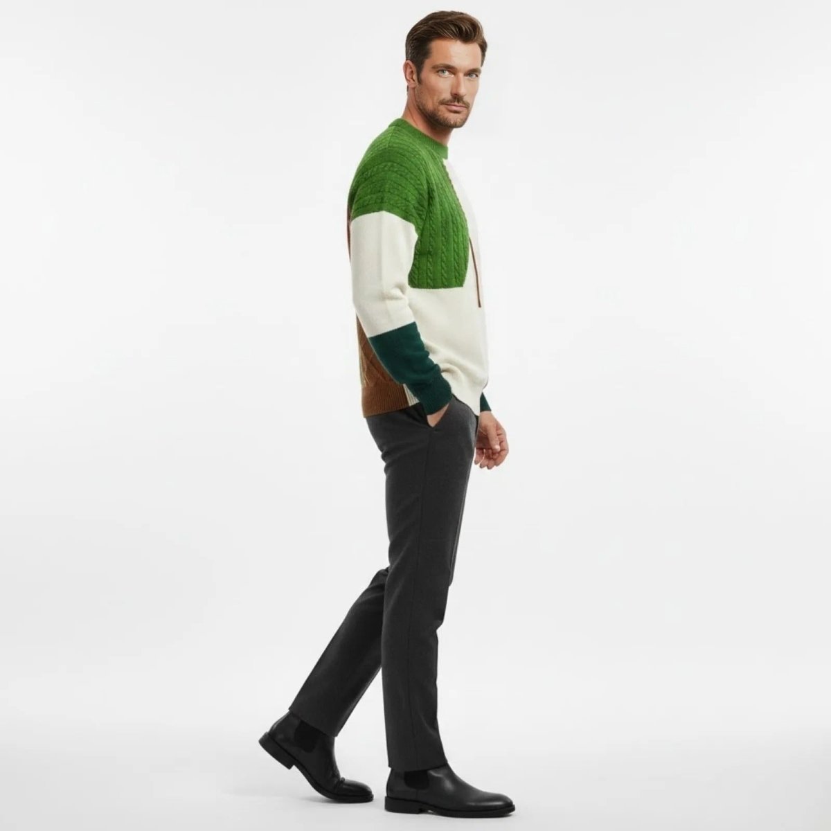 Side view of a male model walking in the Kouvr colorblock sweater, showing the forest green cuff and patchwork sleeve details.