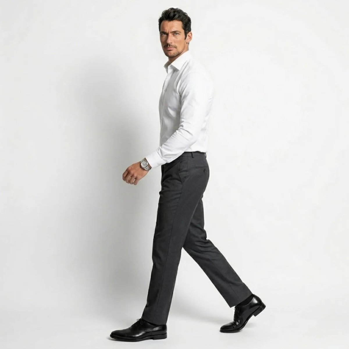 Side profile of male model walking wearing Kouvr fitted white long sleeve dress shirt