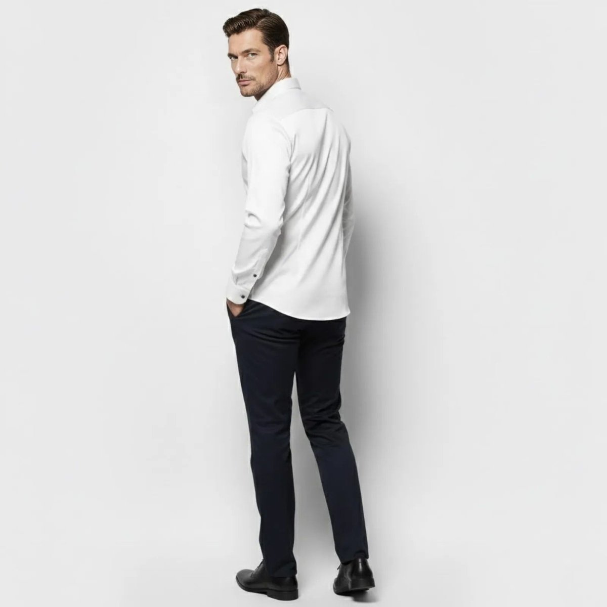 Back view of a male model wearing the Kouvr Fashion white slim fit dress shirt, highlighting the tailored back darts and fit.