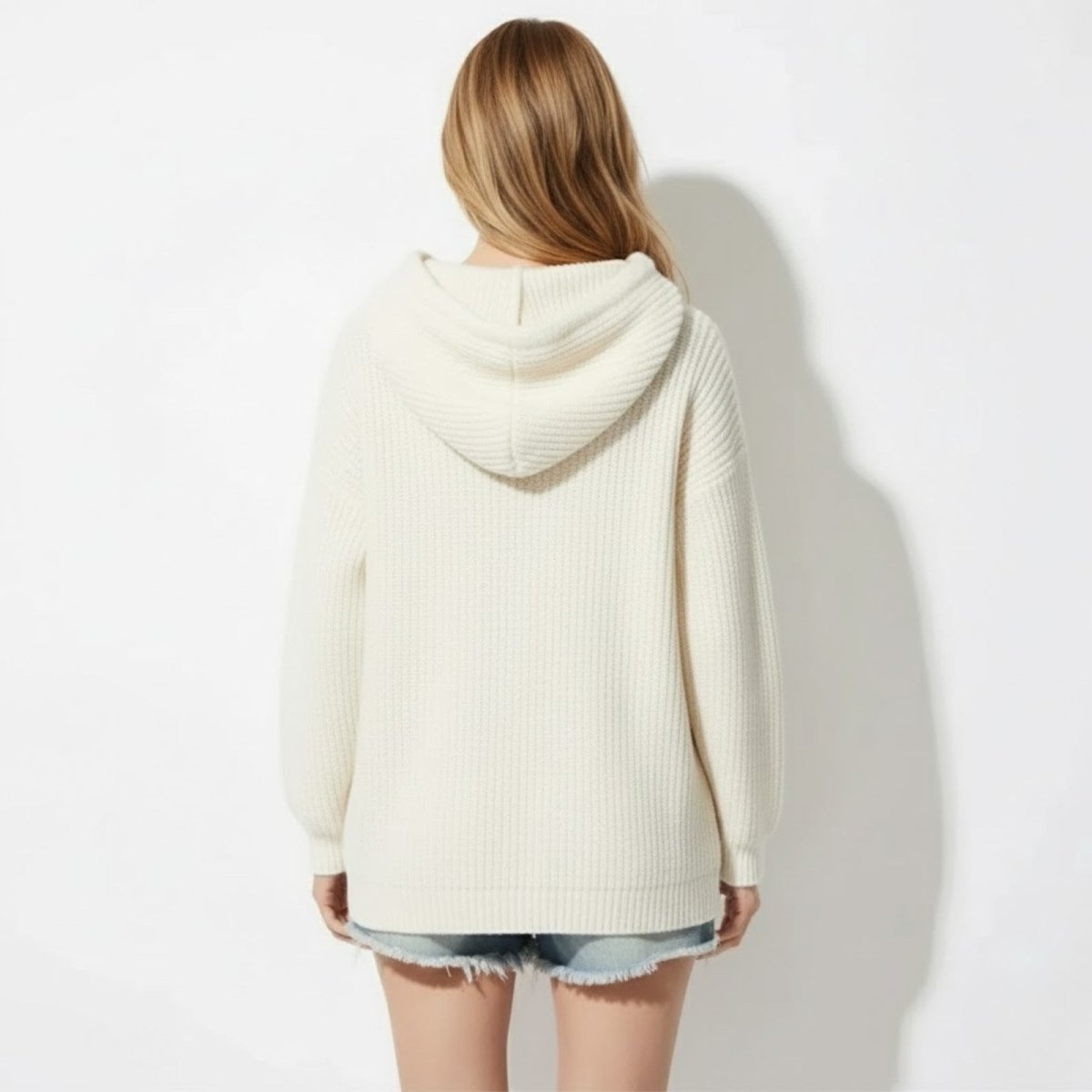 Back view of the Kouvr Nadya oversized off white knit hoodie highlighting the generous hood and ribbed texture.