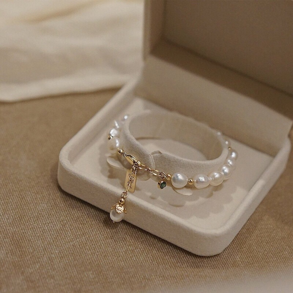 The Kouvr Fashion Nathalia pearl bracelet elegantly displayed inside a sophisticated beige jewelry box, perfect for gifting.