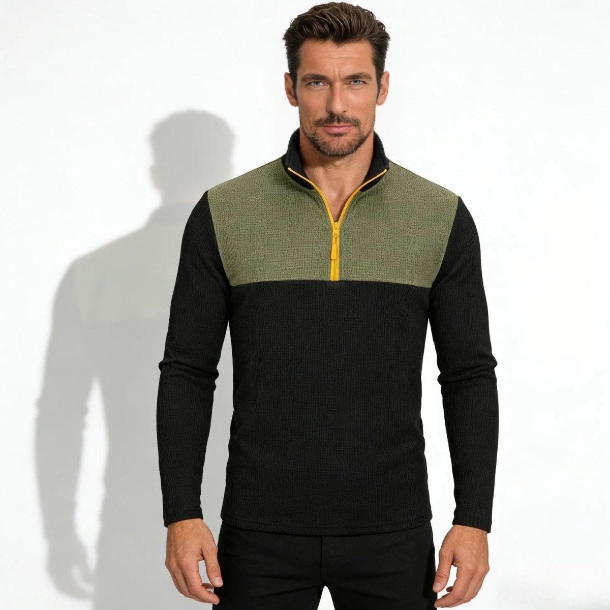 Model wearing the Kouvr Ozzy men's slim fit half-zip sweater in olive green and black, showing the textured waffle knit and yellow zipper detail.