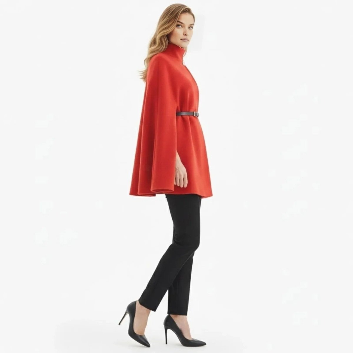 Side profile of a female model walking in the Kouvr red wool-blend cape coat, showing its A-line silhouette and structure.
