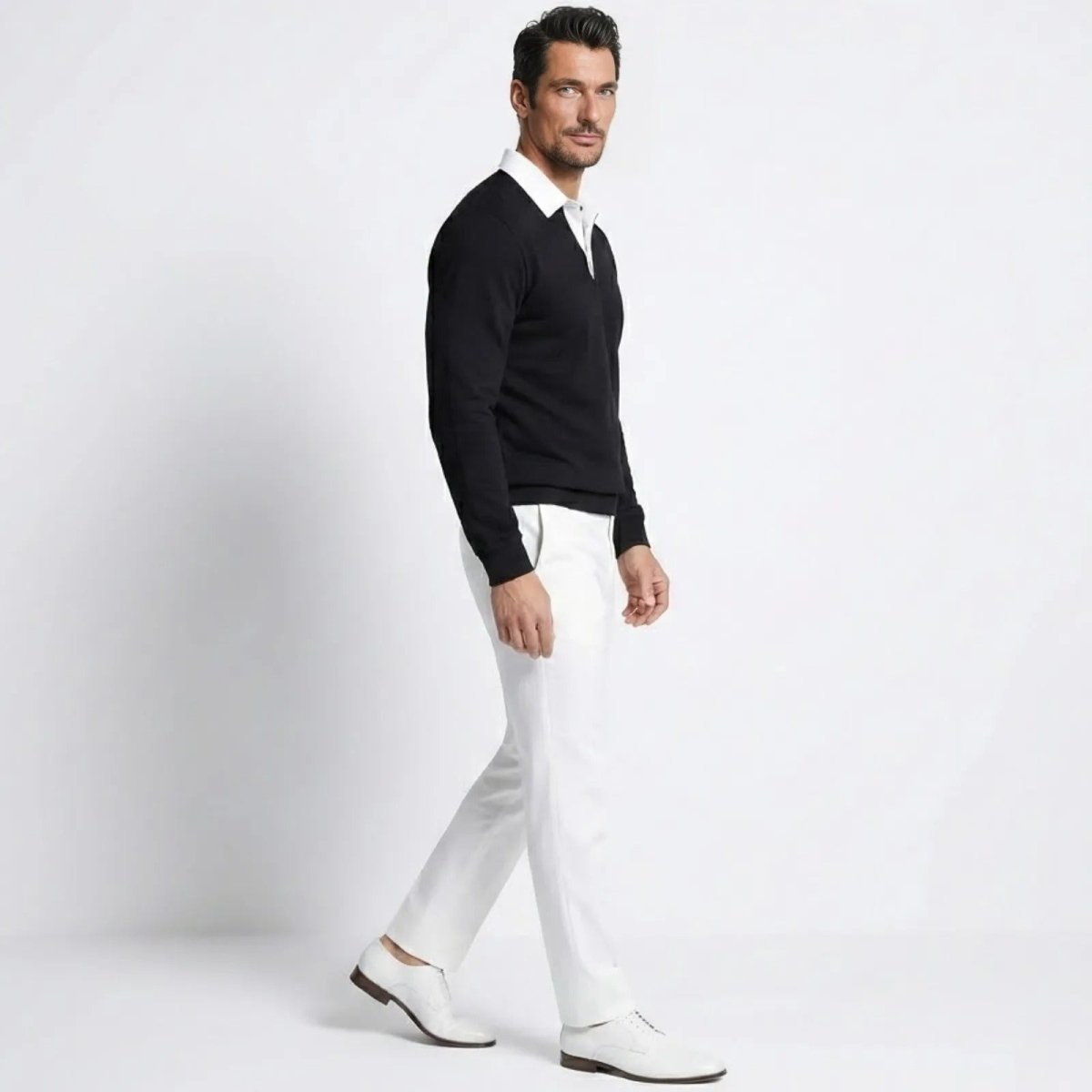 Side view of a male model walking in the Kouvr Rhodes black long sleeve polo sweater, showing the classic fit and drape of the merino-cashmere fabric.