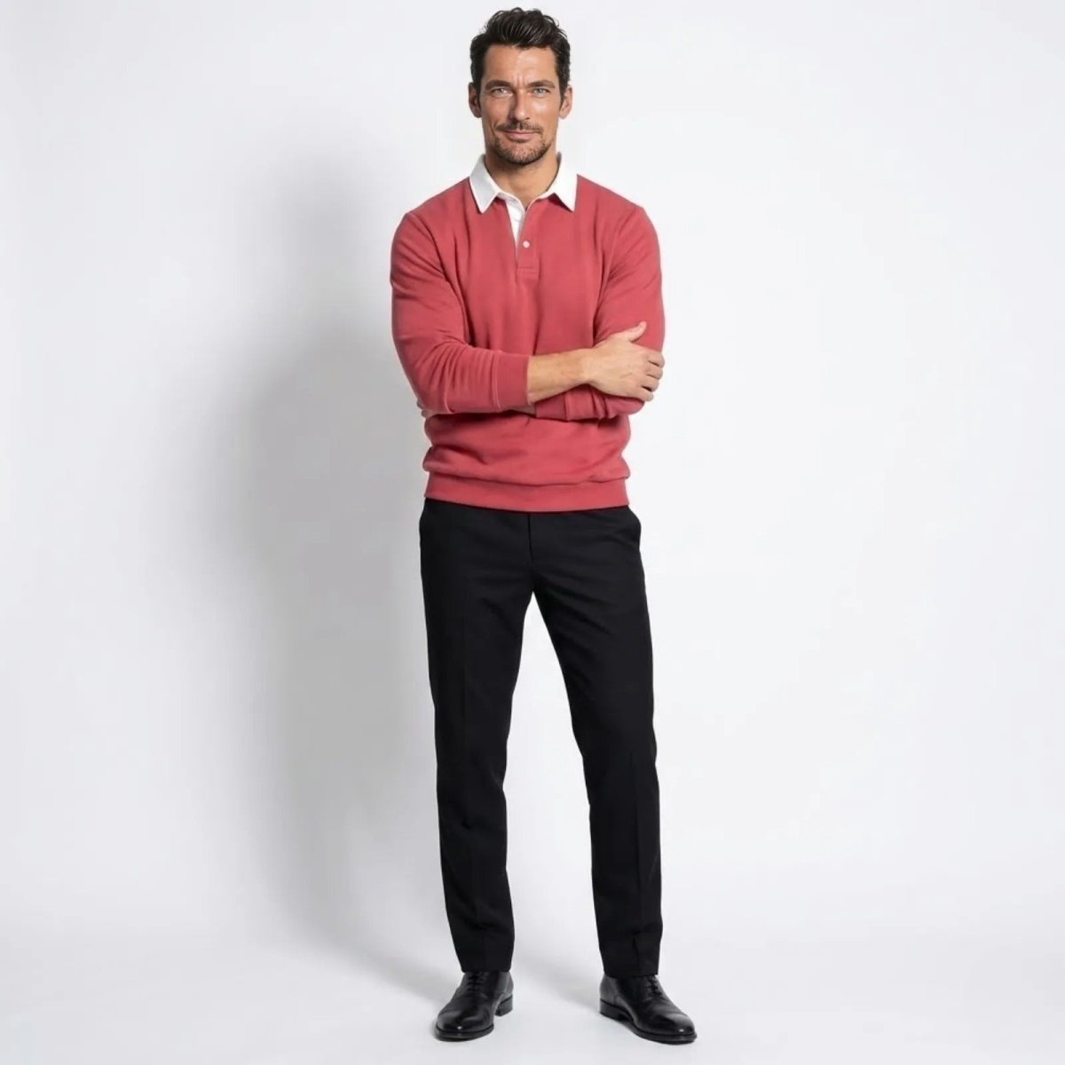 Model wearing the Kouvr Rhodes long sleeve polo sweater in rosewood red, viewed from the front with arms crossed.