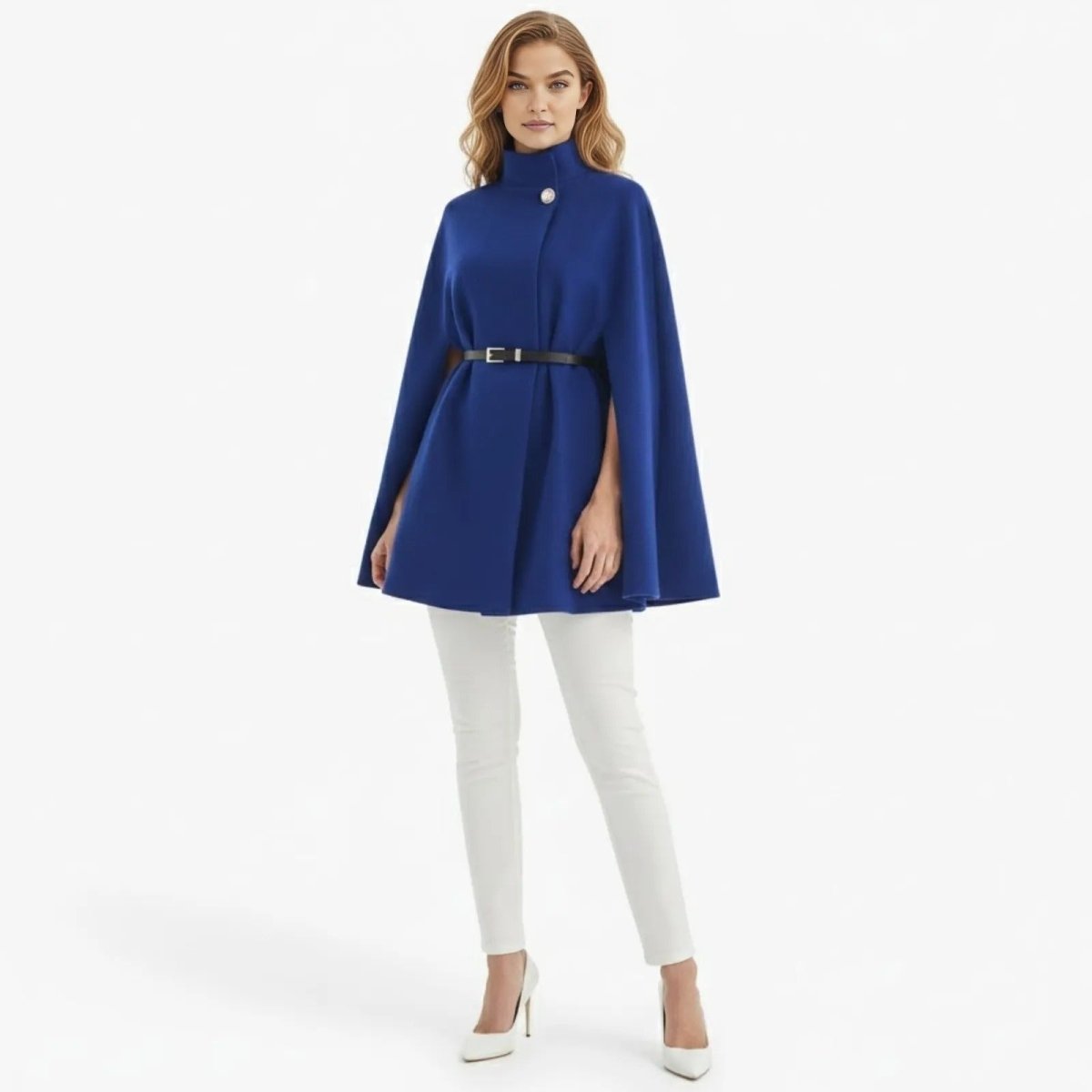 Model wearing the Kouvr royal blue belted wool cape coat with white pants, showing the full structured A-line silhouette and high neck.