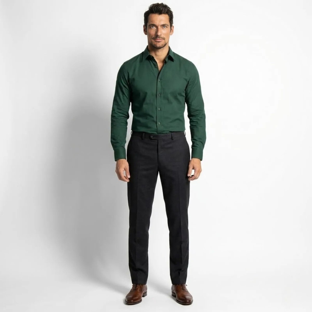 Model wearing the Kouvr Leland men's slim fit dress shirt in Dark green, facing forward, styled with dark charcoal trousers and brown leather shoes.