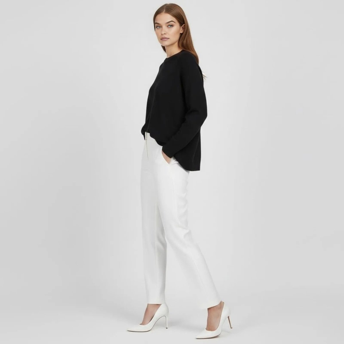 Side view of a model in a relaxed fit black merino wool sweater showing its drape and dolman sleeves.