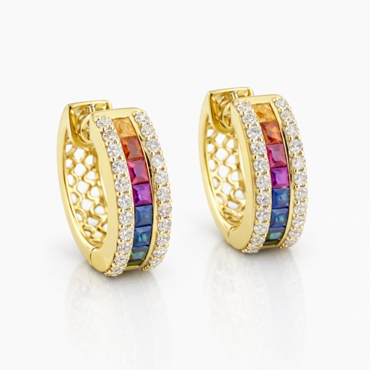 A pair of Kouvr Yasmina 18k gold huggie hoop earrings with a central channel of square-cut rainbow gemstones, flanked by pavé diamonds, on a clean white background.