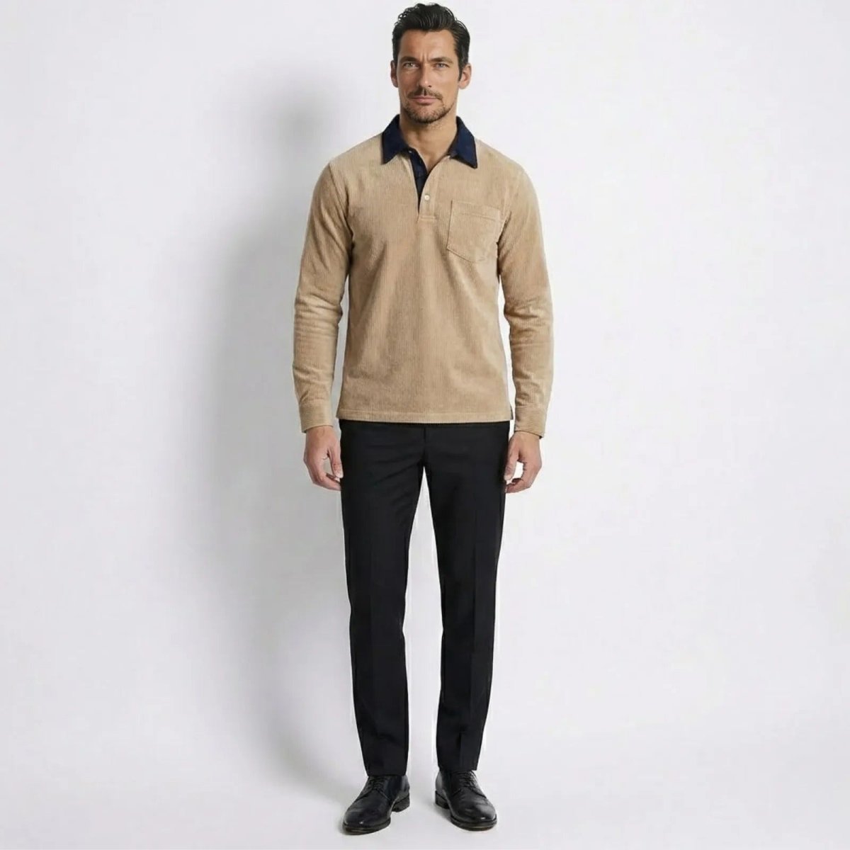 Model wearing the Kouvr Zian Corduroy Long Sleeve Polo in khaki with a navy contrast collar, styled with black trousers.
