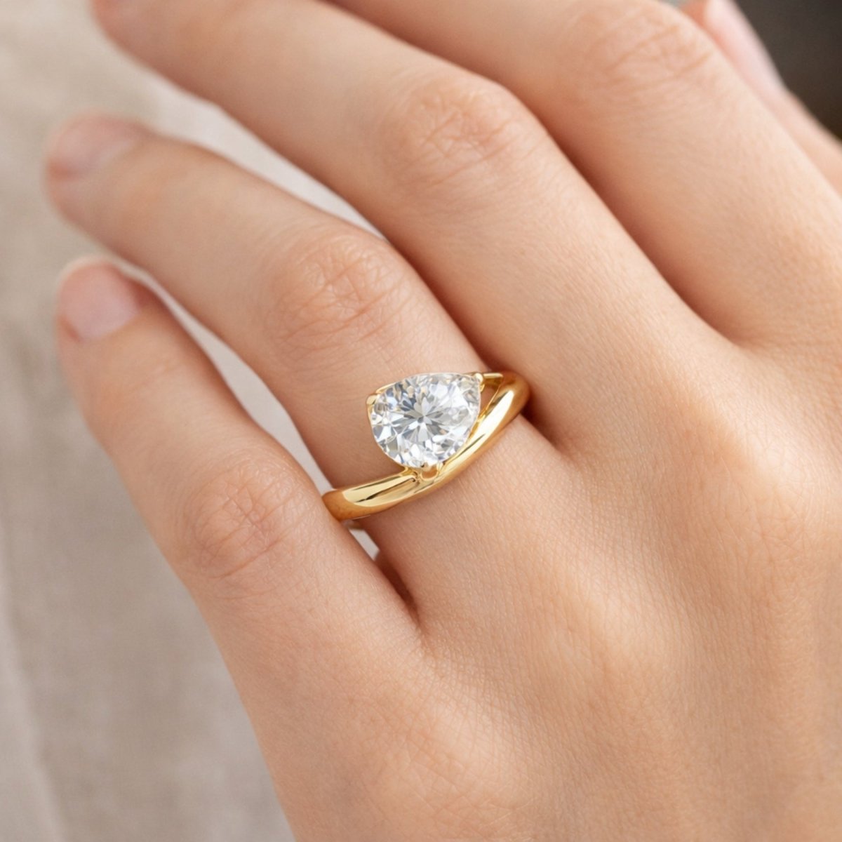 Profile view of a hand wearing the Kouvr Zoella heart shaped diamond ring, showing the asymmetrical gold band.