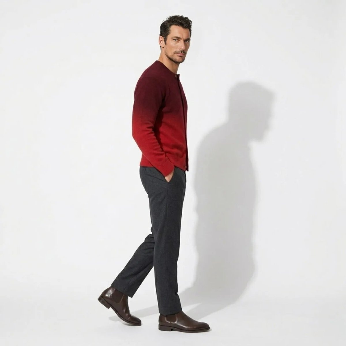 Side profile of man walking confidently in Kouvr premium red gradient button up crew neck knitwear.